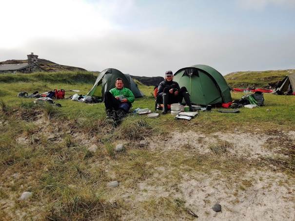 A group of people sitting in front of tents in a field

Description automatically generated with medium confidence