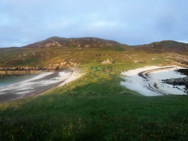 A grassy area with a body of water and hills in the background

Description automatically generated with low confidence