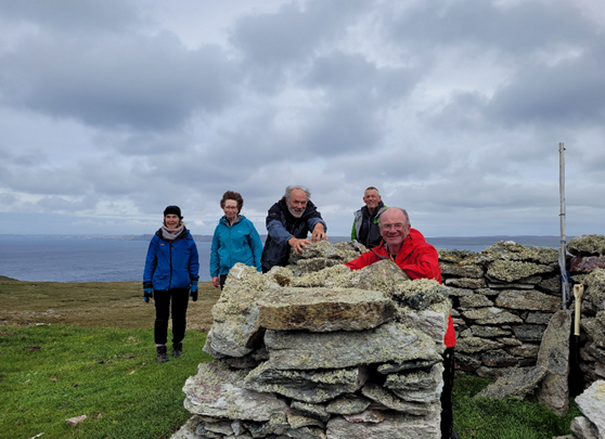 A group of people standing around a rock structure with a body of water in the background

Description automatically generated with low confidence