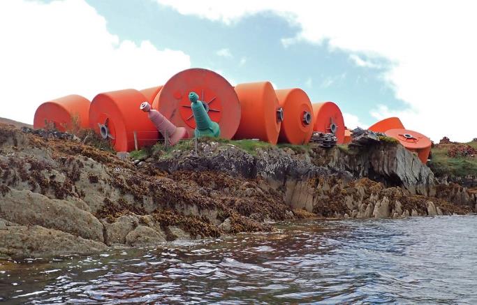 A group of orange barrels on a rocky shore

Description automatically generated