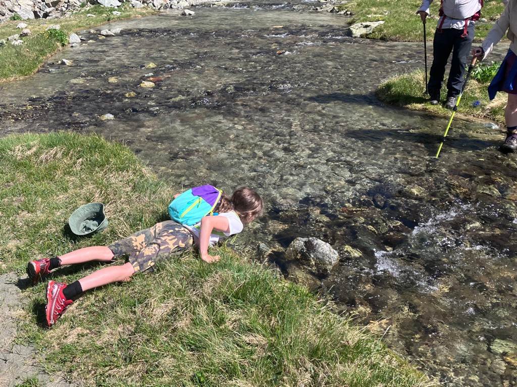 A child lying on the ground by a river
Description automatically generated