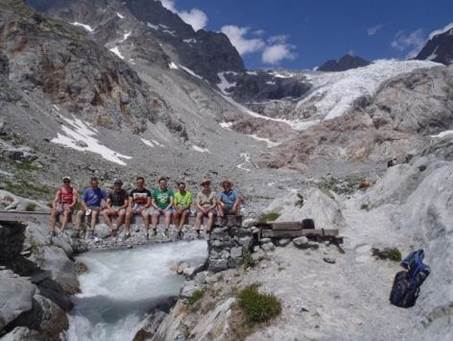 A group of people sitting on a bridge over a river

Description automatically generated