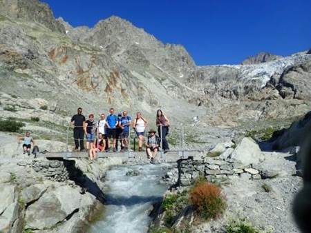 A group of people standing on a bridge over a river

Description automatically generated