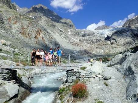 A group of people standing on a bridge over a river

Description automatically generated