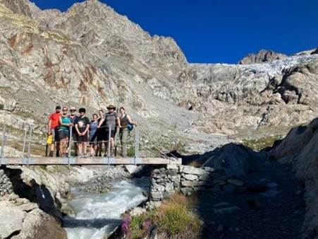 A group of people standing on a bridge over a river

Description automatically generated