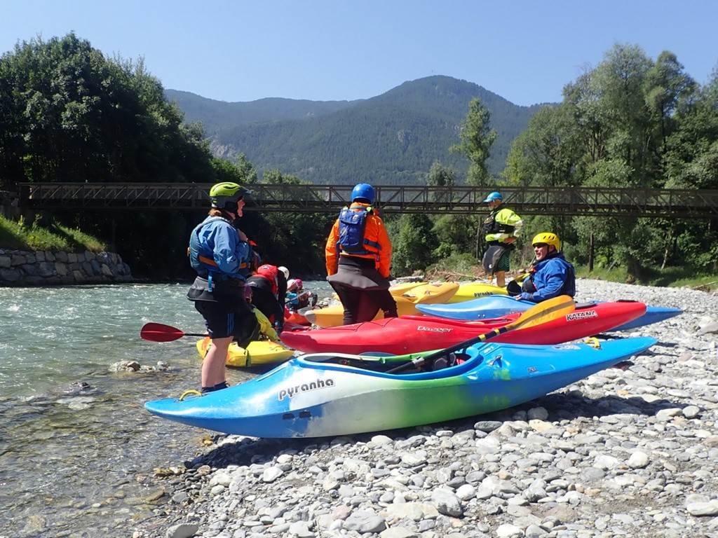 A group of people in kayaks on a rocky riverbank
Description automatically generated