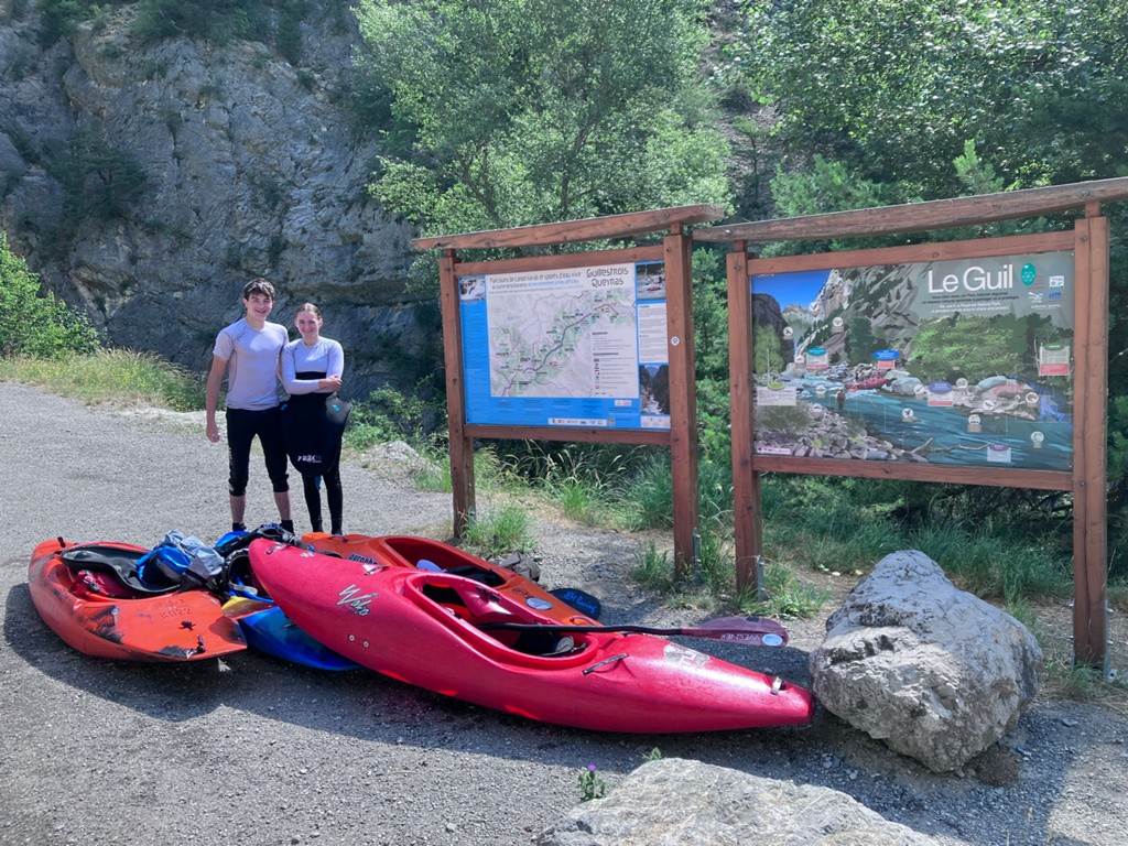 Two people standing next to a sign
Description automatically generated