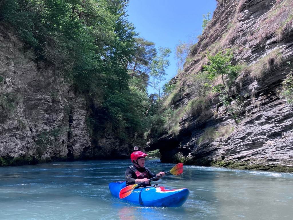 A person in a kayak on a river
Description automatically generated