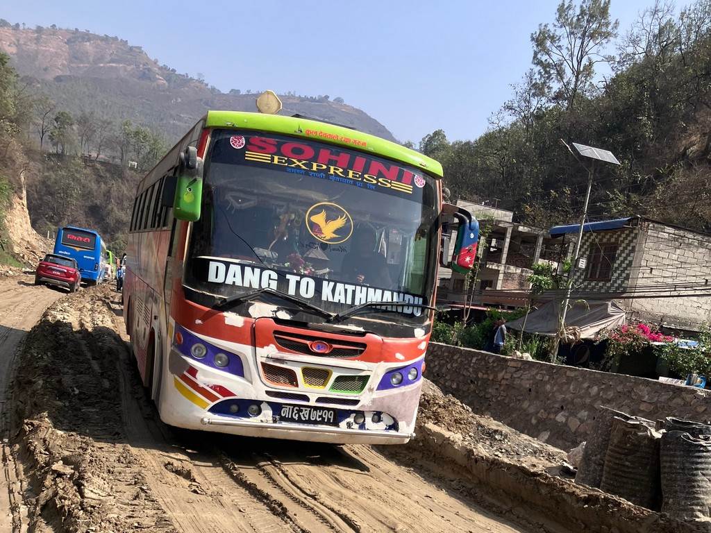 A bus driving on a dirt road

Description automatically generated