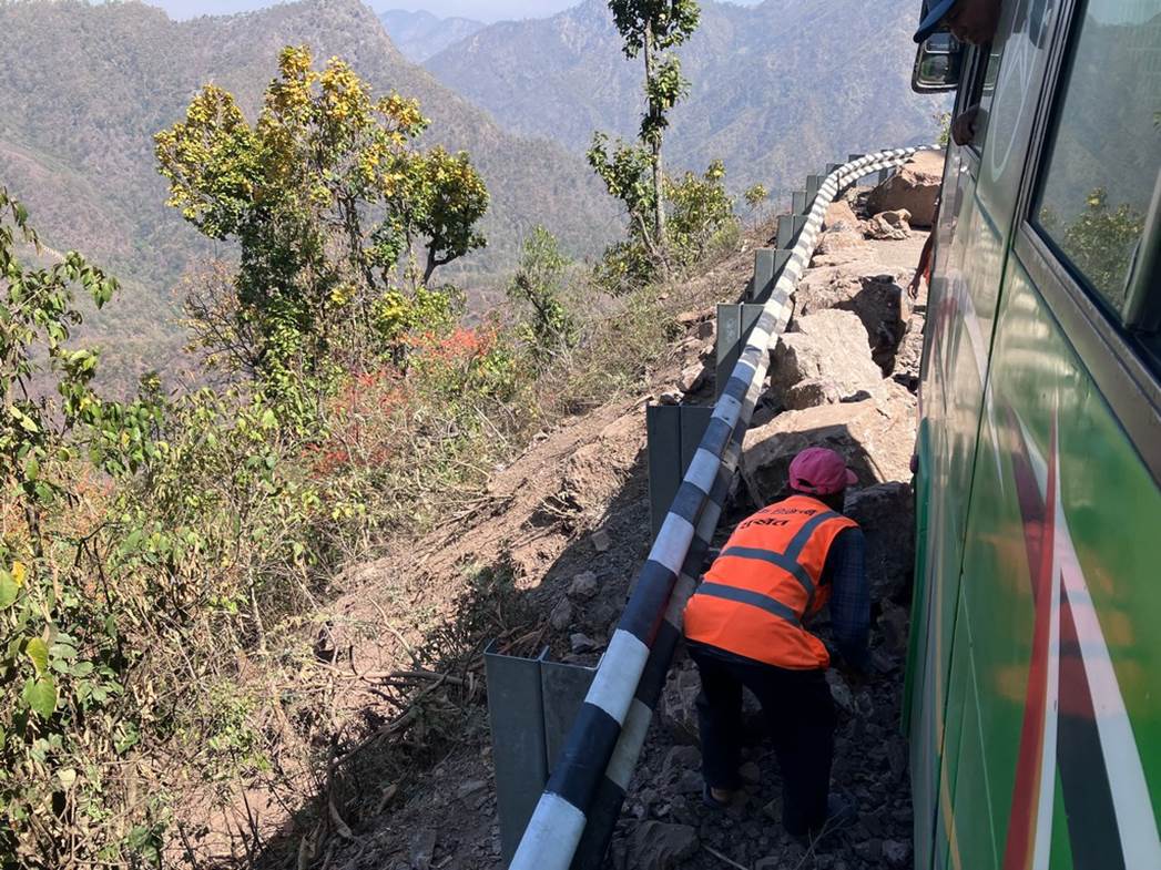 A person in orange vest on a mountain side

Description automatically generated