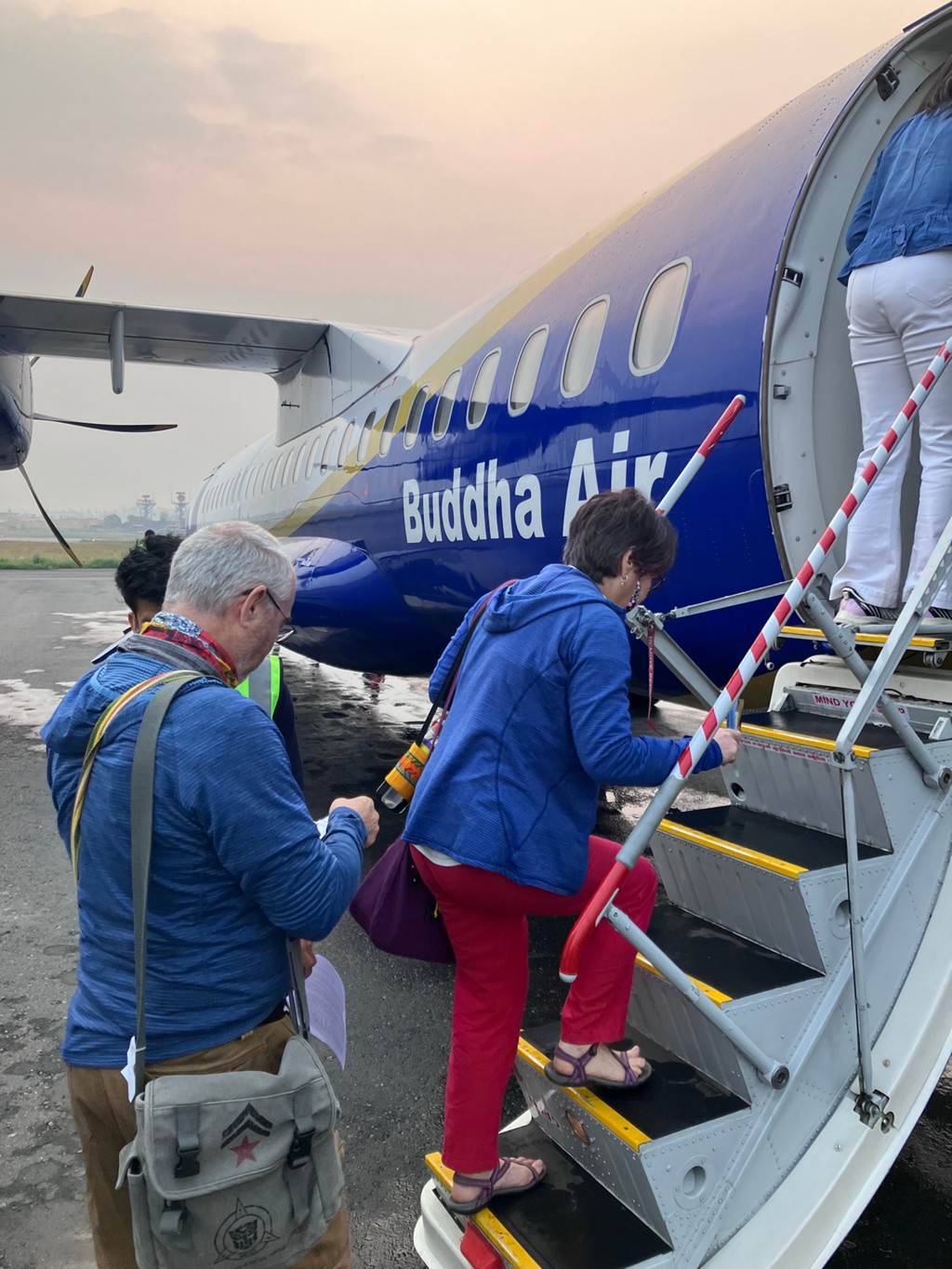 People walking up the stairs of an airplane

Description automatically generated