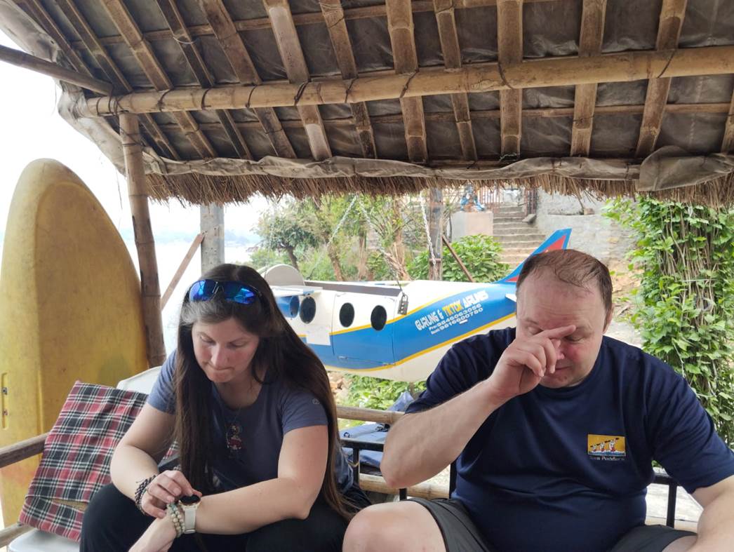 A person and person sitting under a straw roof

Description automatically generated