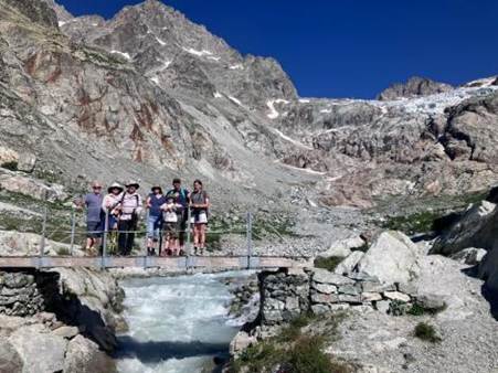 A group of people standing on a bridge over a river

Description automatically generated